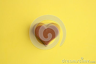 Top view of a chocolate heart-shaped bonbon isolated on a yellow background Stock Photo