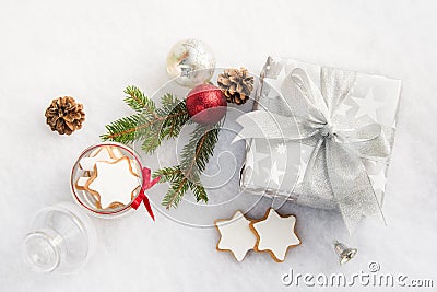 Top view of a christmas gift box in silver wrapping paper over a white fluffy background. A jar full of star cookies and christma Stock Photo