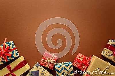 Top view on Christmas gifts wrapped in gift paper decorated with ribbon on brown paper background. Stock Photo