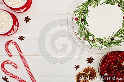 Top view of christmas pie, viburnum berries, candy canes and two cups of cocoa with marshmallows on white wooden table . Stock Photo