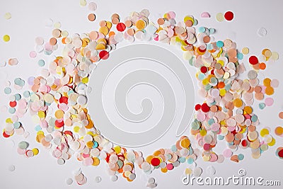 top view of circle of colored confetti pieces on white surface Stock Photo