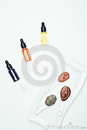 top view of clay powder, cosmetic bottles with pipes, plate and spoons with various colorful clay masks Stock Photo