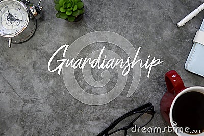 Top view of clock,plant,eyeglasses, a cup of coffee,notebook and pen on grey floor written with Guardianship Stock Photo