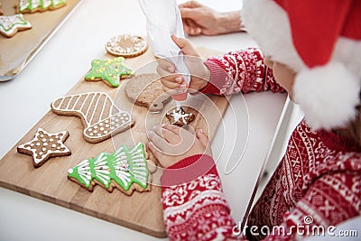 Concentrated female child squeezing cream on Christmas pastry Stock Photo