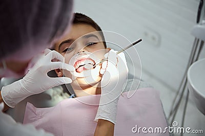 Top view. Close-up of little boy wearing a dental cheek retractor during regular medical check-up. Dentist using stainless steel Stock Photo