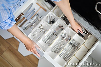 Top view closeup housewife hands tidying up cutlery in drawer general cleaning at kitchen Stock Photo