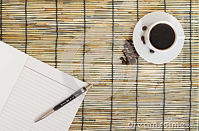 Top view of Coffee beans with white cup, blank notebook and pen on mat Stock Photo