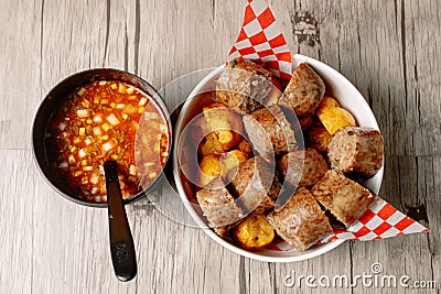 Top view of colombian morcilla blood sausage and a bowl of vegetable soup on a wooden table Stock Photo