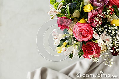 Top view of a colorful bouquet of beautiful flowers in the corner and gray blurry background with a piece of fabric Stock Photo