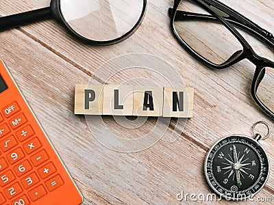 Top view compass,eye glasses,calculator and magnifying glass with text PLAN written on wooden cubes. Stock Photo