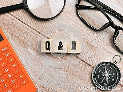 Top view compass,eye glasses,calculator and magnifying glass with text Q AND A written on wooden cubes. Stock Photo