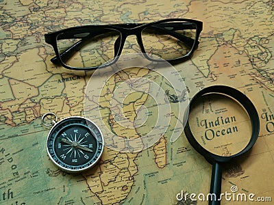 Top view compass, eye glasses and magnifier on world map. Travel and holiday concept. Stock Photo