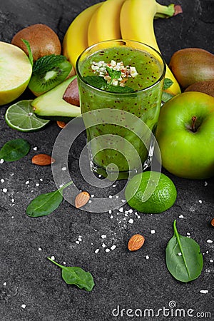 Healthful fruits and a glass of cocktail from kiwi on a dark gray stone background. Juicy ingredients for vegan diets. Stock Photo