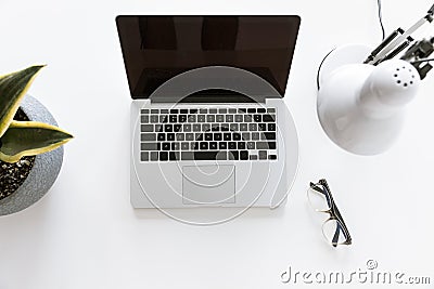 Top view of composition with laptop on white tabletop with glasses, desklamp Stock Photo