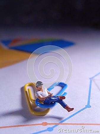 Top View, Conceptual Close Up Photo, Mini Figure toy Man Holding Smartphone, Sit at paperclip, Check Business Report Stock Photo