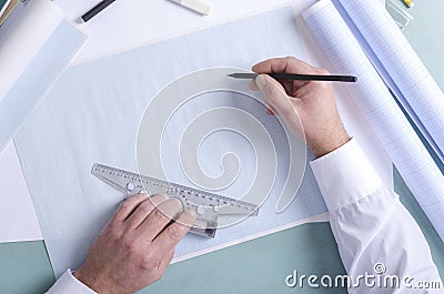 Top view of constuctor`s hands who using t-square and pencil. Draftsman at work, drafting on the graph paper. Free space for desig Stock Photo