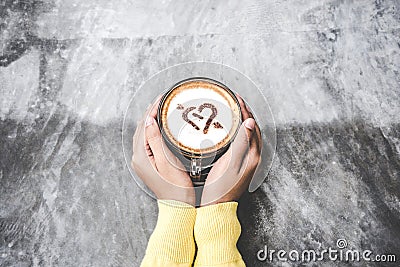 Top view with copy space. Hand women holding coffee love on cement table, vintage tone. Stock Photo