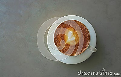 A cup of cappuccino coffee decorated with heart pattern on brown milk froth in white Stock Photo