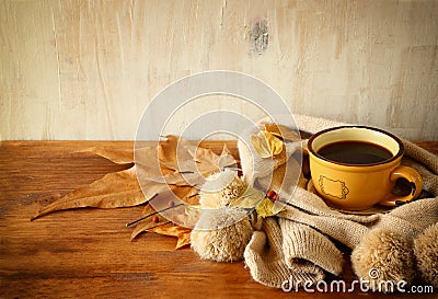 Top view of Cup of black coffee with autumn leaves, a warm scarf on wooden background. filreted image. Stock Photo