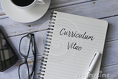 Top view of a cup of coffee,mobile phone,glasses,pen and book written with Curriculum Vitae on wooden background Stock Photo