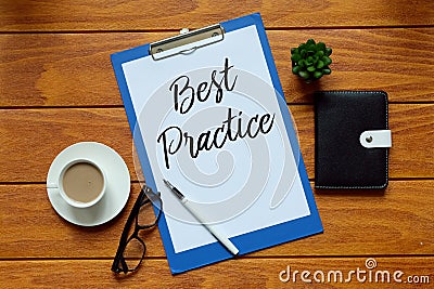 Top view of a cup of coffee,pen,sunglasses,notebook,plant and paper written with Best Practice on wooden background. Stock Photo