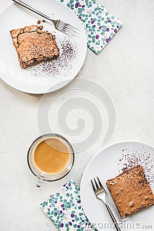 Top view of a cup of coffee and two dessert plates with brownie cake over white rustic background Stock Photo