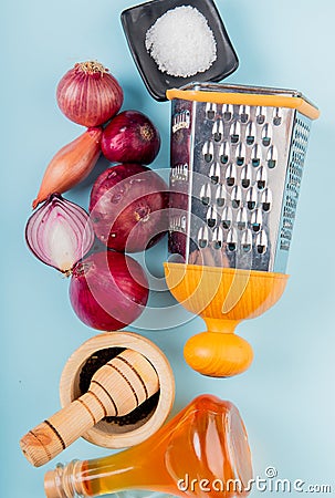 top view of cut and whole onions with melted butter, black pepper, salt and grater on blue background Stock Photo