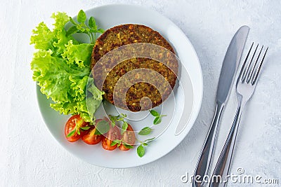 Top view of cutlets with vegetable mix, salads, tomatoes, knife, and fork on white table Stock Photo