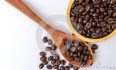 Top view of dark brown roasted organic coffee bean in a wooden bowl and spoon on white background. Selective focus on coffee beans Stock Photo