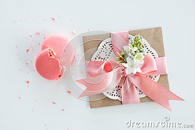 Top view of decorative kraft envelope with bow and pink macarons on white Stock Photo