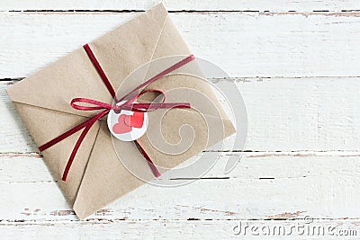 Top view of decorative kraft envelope with tag and ribbon on wooden tabletop Stock Photo