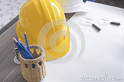 Top view of desk of engineering project in construction site or office with stationery and yellow safety helmet. Construction and Stock Photo