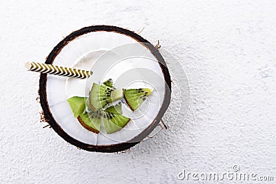 Top view dessert with cream and kiwi in coconut bowl with straw on white background Stock Photo