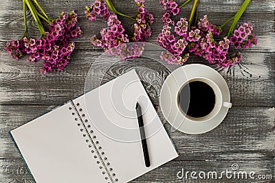 Top view of a diary or notebook, pencil and coffee and a purple flower on a gray wooden table. Flat design. Stock Photo