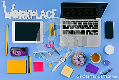 Top view of digital devices, inscription workplace and office supplies with doughnut and coffee Stock Photo