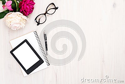 Top view E-reader, paper notepad, glasses and pen on wooden background. Flat lay woman accessories, feminine desk with e-book and Stock Photo