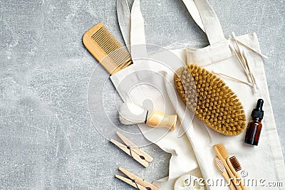 Top view eco-friendly bath accessories with canvas bag on stone table. Flat lay wooden hair comb, brush, essential oil, loofah Stock Photo