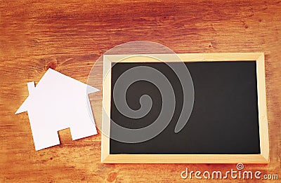 Top view of empty blackboard with room for text and house shaped paper cut over wooden table Stock Photo