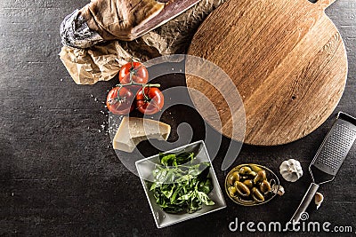 Top of view empty pizza board tomatoes olives garlic basil parmesan cheese and prosciutto Stock Photo