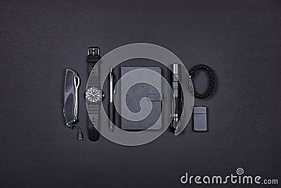 Everyday carry EDC items in black color - knife, lighter, note book, tactical pen, watch, survival bracelet and flashlight. Stock Photo