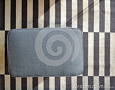 Top view of fabric blue rectangular pouf on blue and white striped carpet Stock Photo