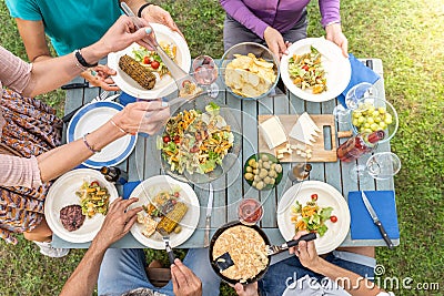 Top view of family sitting at wooden table having dinner. They have plates full of food and glasses with drinks. Stock Photo