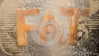 TOP VIEW: FAT letters fry in oil in a pan - steam and boils Stock Photo