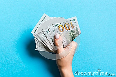 Top view of female hand holding a pack of money on colorful background. One hundred dollars. Business concept. Charity and tips Stock Photo