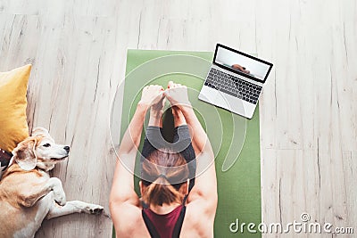 Top view at fit sporty healthy woman sit on mat in Paschimottanasana pose, doing breathing exercises, watching online yoga class Stock Photo