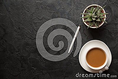 Top view flat lay shot of office desk table. Cup of cappucino coffee, plant pot and pen on dark background. Copy space Stock Photo