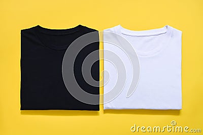 Top view of folded black and white color t-shirt on yellow background, copy space, flat lay Stock Photo