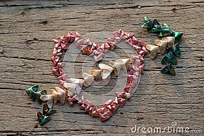 Top view of folding paper in little heart shape put on the wooden plate in the heart shapeand cupid arrow Stock Photo