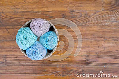 Top view of four cotton balls in blue, mint, turosque and beige colors, assorted in small basket on brown wooden texture with much Stock Photo