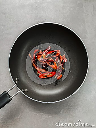 Fried black peppers, chillies, dried chilli on the black pan. Stock Photo